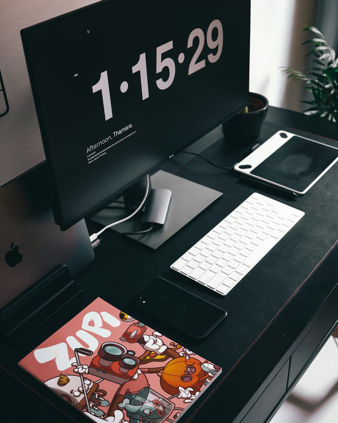 Modern desk with computer, laptop, keyboard, and plant.